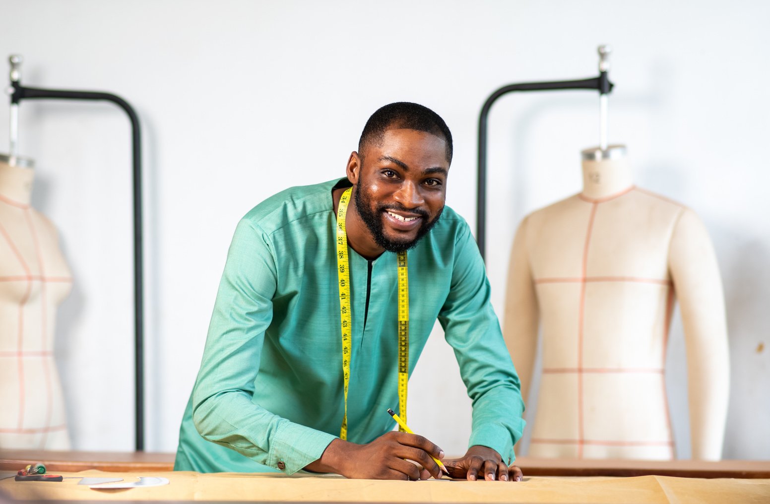 Young cheerful African- American tailor working in a tailor studio